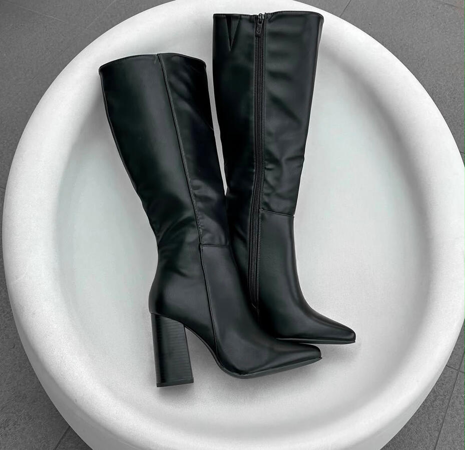 Bota negra alta de acabado liso con cierre lateral y taco ancho. Elegante, cómoda y versátil.